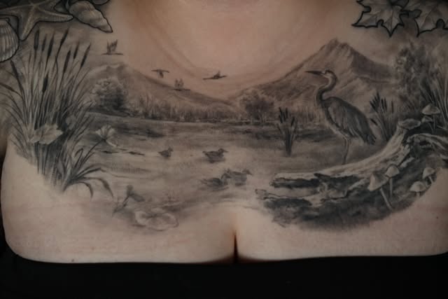 Wide black and grey landscape tattoo across the lower back